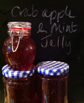 stacked jars of finished crab apple jelly in front of a blackboard